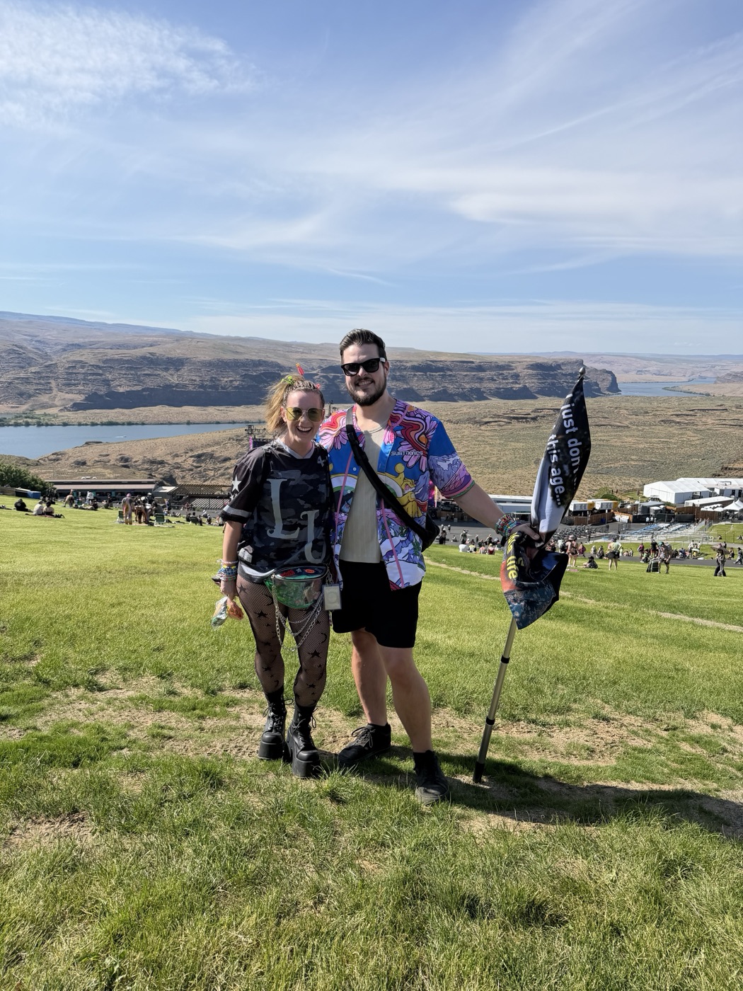 Tay and Jake on the lawn at the Gorge, the Columbia River behind them, Jake holding a flag